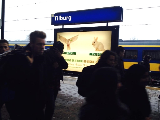 Een banner op station Tilburg met een duif met de tekst 'Kerstgedachte', een konijn met 'Kerstdiner?' en 'Vrede begint op je bord. Go vegan'