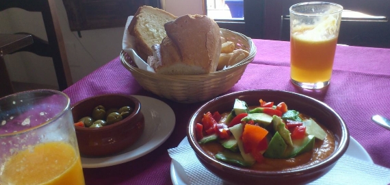 een salade, brood, olijven en twee glazen met sap