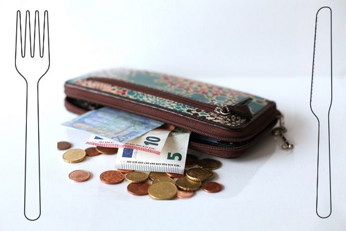 Tussen bestek ligt een portemonnee gevuld met geld