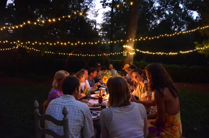 Summer Dinner Party van groep mensen die samen vegan eten aan een lange tafel bij schemering