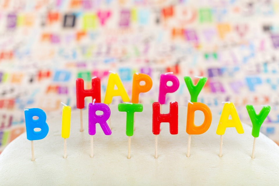 Gekleurde letter-kaarsjes in een taart die de woorden 'happy birthday' spellen