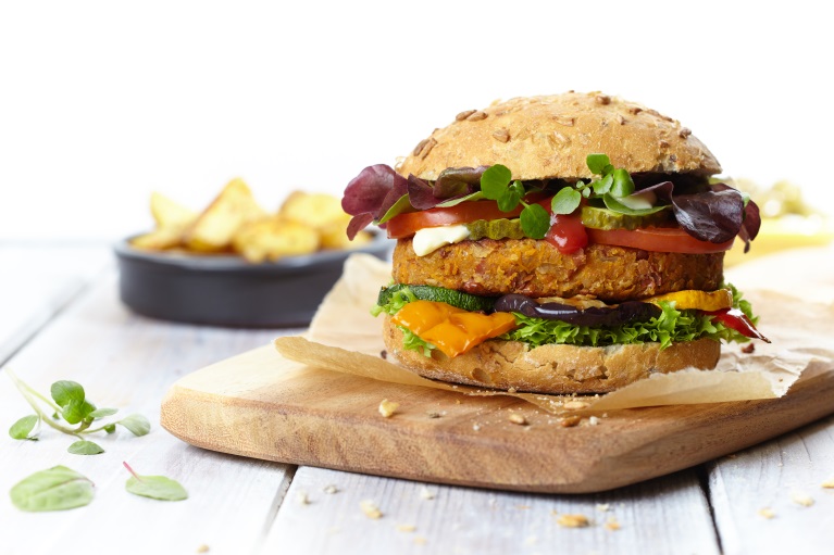 De vleesvervanger voer voor veganburgers Rijk belegde vegan hamburger geserveerd op houten plank