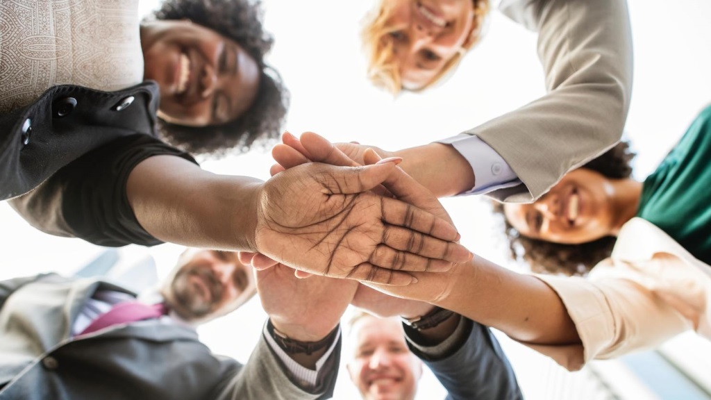mensen leggen hun handen boven op elkaar