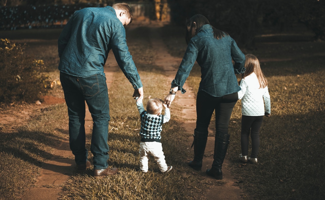 twee volwassenen lopen met twee kinderen in een bos