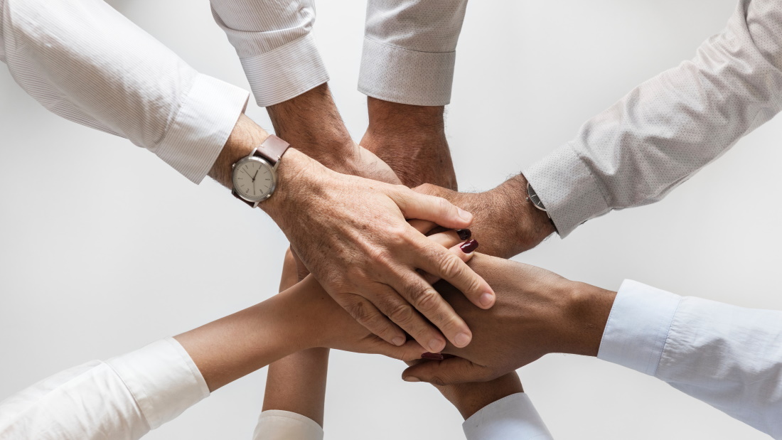 mensen leggen hun handen bovenop elkaar