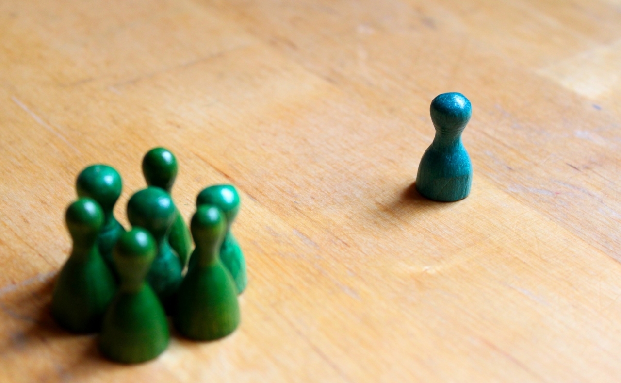 een blauwe pion op afstand van een groepje groene pionnen