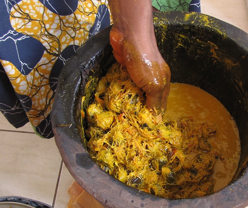 Palmolie handproductie een hand in een emmer met oliepalmvruchtvezels en palmolie