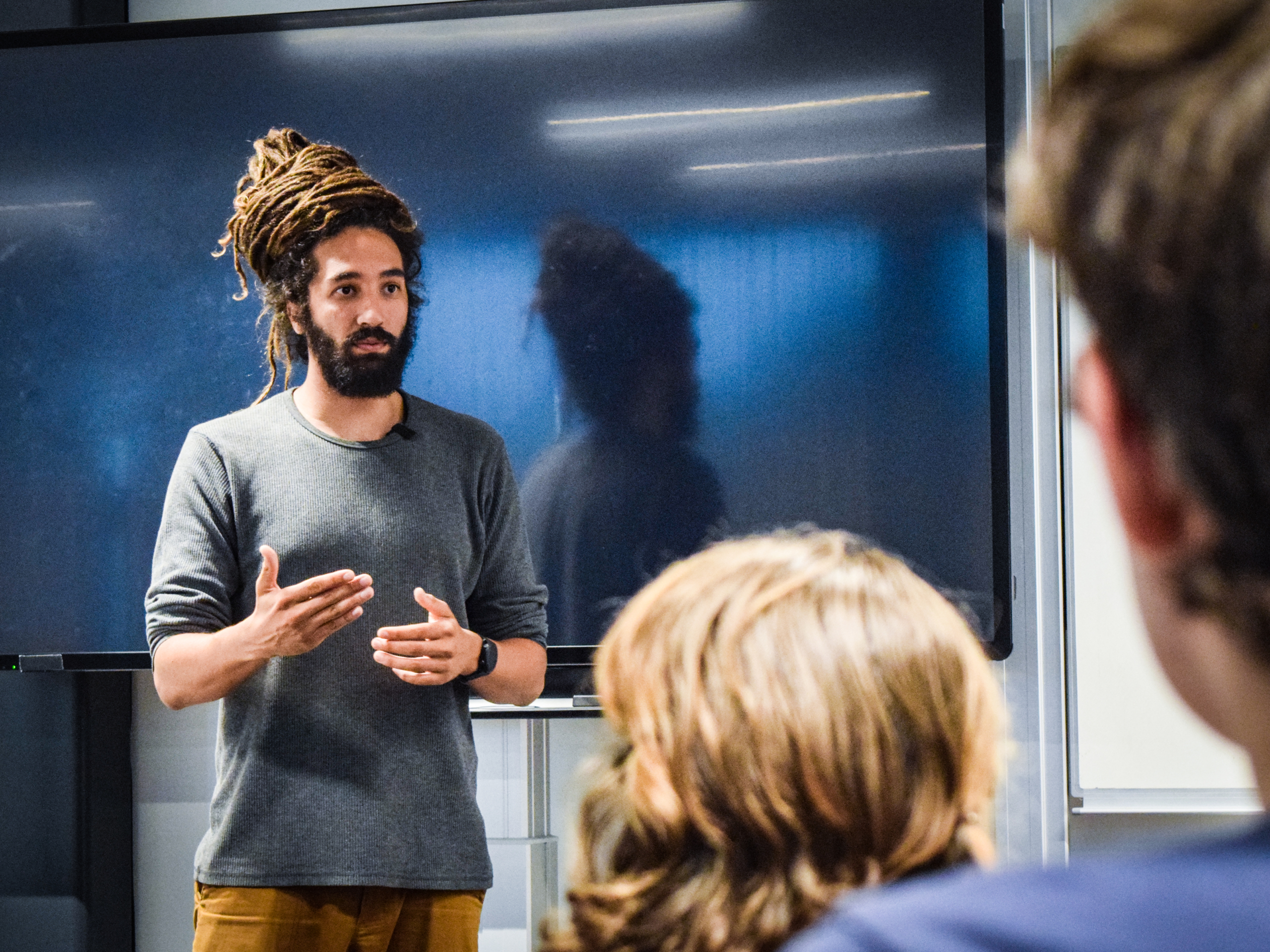 20220525-181728-001 een persoon staat voor een digitaal schoolbord en legt iets uit aan anderen