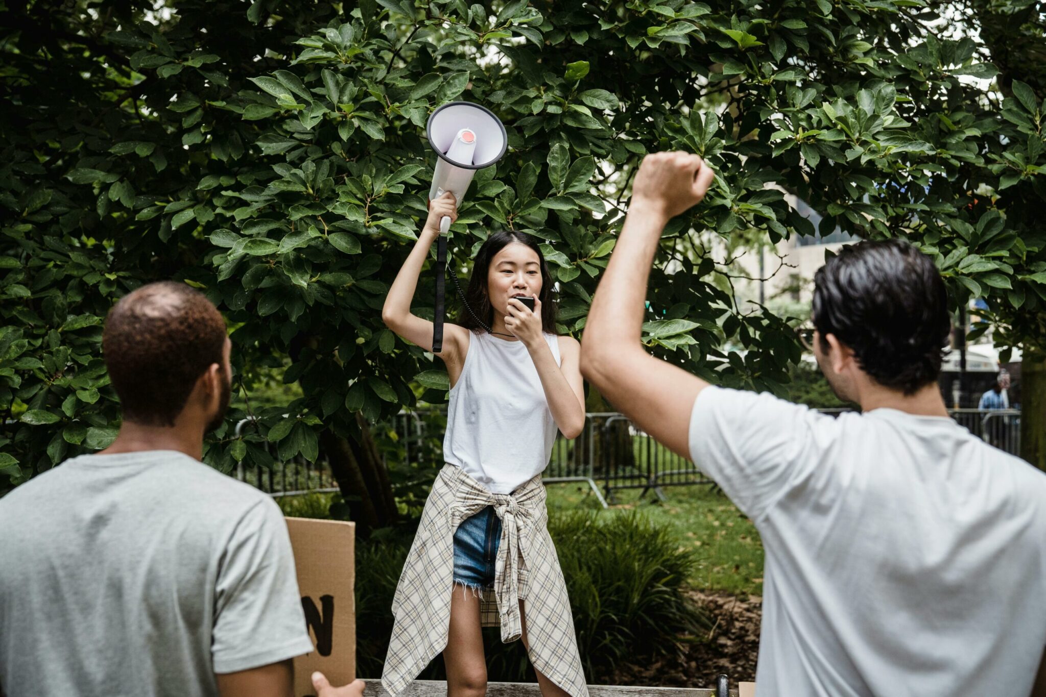 Iemand roept iets door een luidspreker terwijl een andere persoon een gebalde vuist in de lucht steekt.