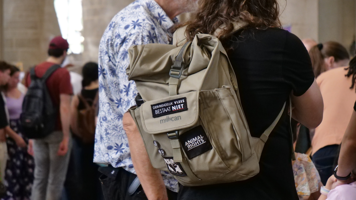 nlvegan-fair_leuzen-tas_Animal-Rights Bezoeker met rugzak waarop de tekst staat 'Diervriendelijk vlees bestaat NIET'.