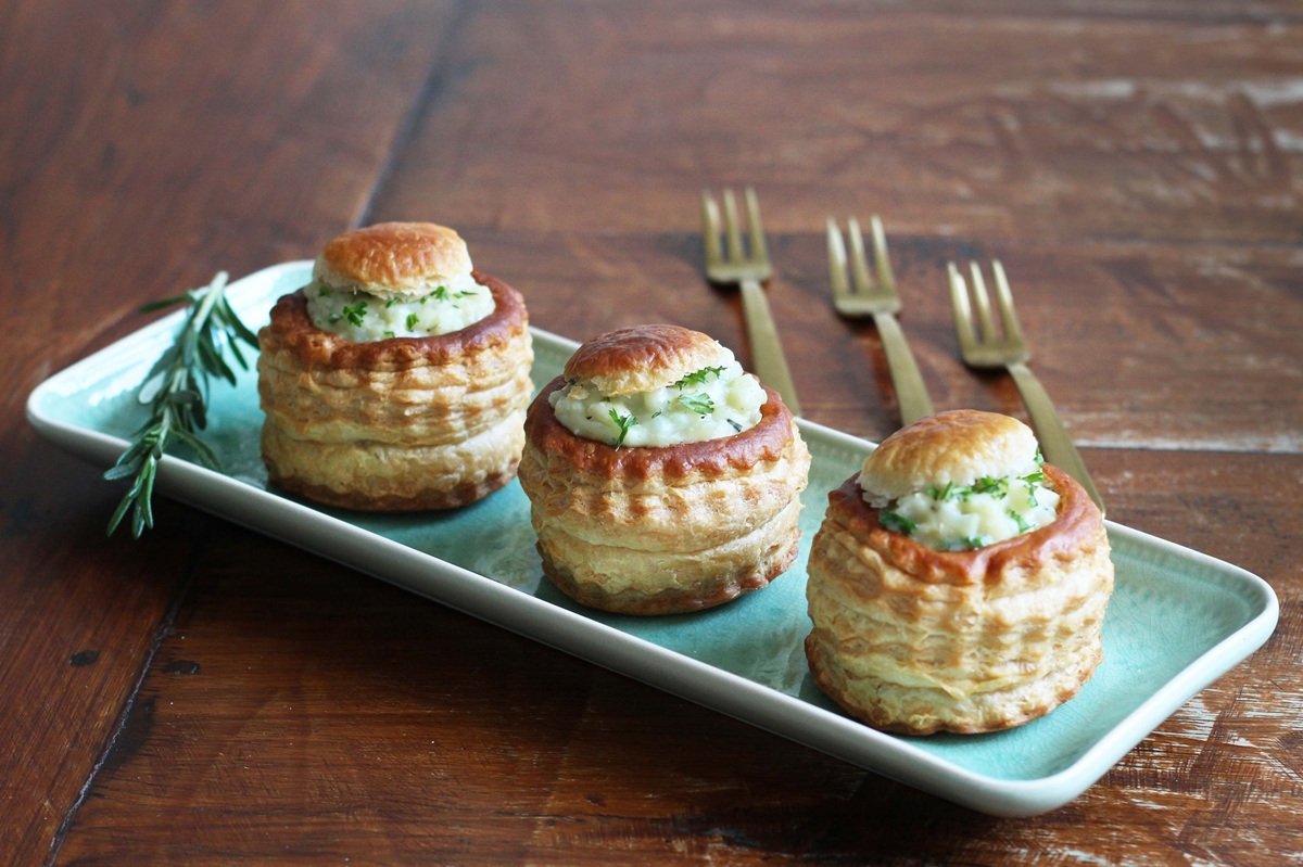Drie pasteitjes met bloemkoolragout op een schaaltje. Op de achtergrond drie goudkleurige vorken.