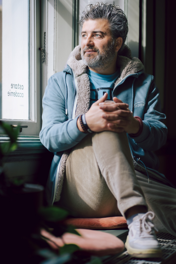 @Marijke-Hoebee-Pepijn-van-der-Weide-4 Pepijn van der Weide zit naast een raam en kijkt erdoor naar buiten.