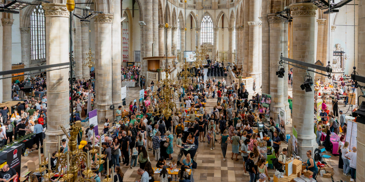 NLVegan-fair-2024-laurenskerk Bovenaanzicht van een grote groep mensen die in de Laurenskerk lopen langs allerlei stands tijdens de NLVegan Fair.