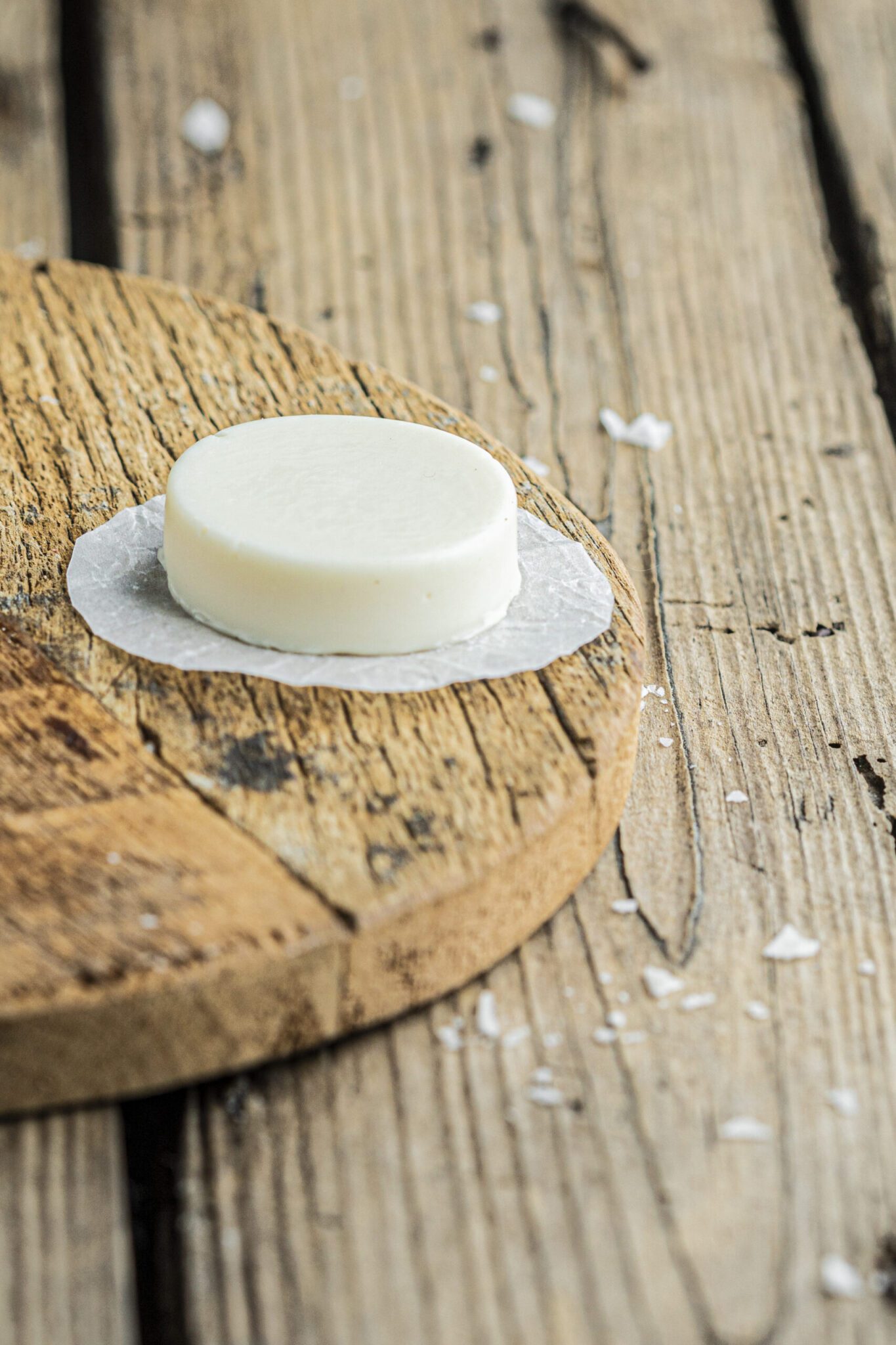 kaas-those-vegan-cowboys Foto van een rond blokje vegan kaas op een houten tafel.